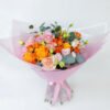 A bouquet of orange roses, pink roses, cream carnations and pink eustomas