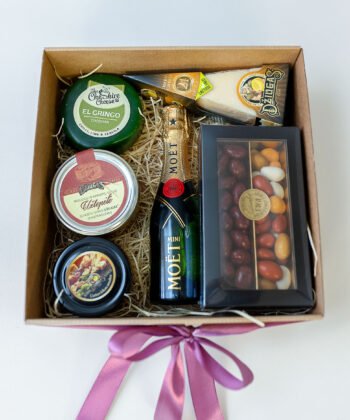 A box with various cheese, honey, sweets and champagne