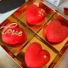 4 красных торта в форме сердечек в золотой коробке.