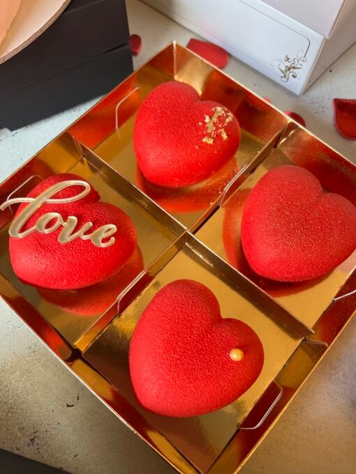 4 red heart-shaped cakes in a golden box